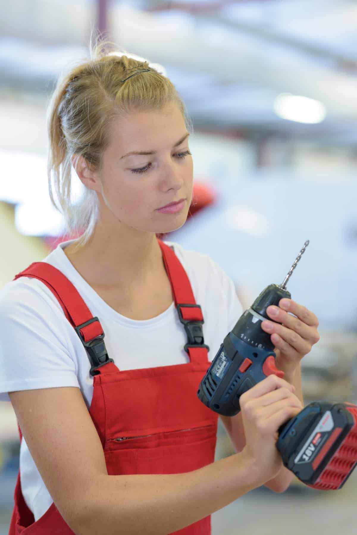 cute woman at work using drilling machine